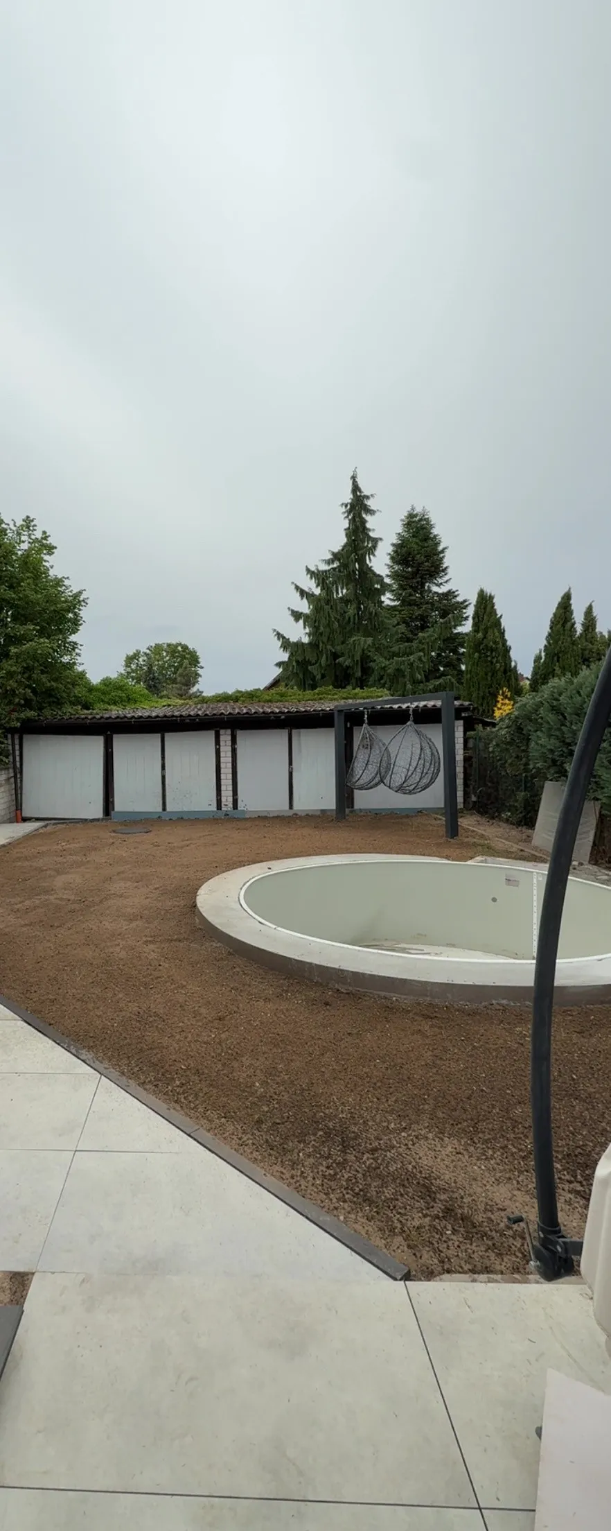 Neu angelegter Garten mit Pool, Terrassenplatten und vorbereiteter Rasenfläche
